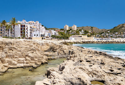 Scenic view of sea by buildings against clear blue sky