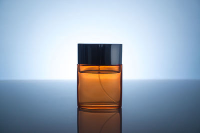 Close-up of perfume on table against colored background