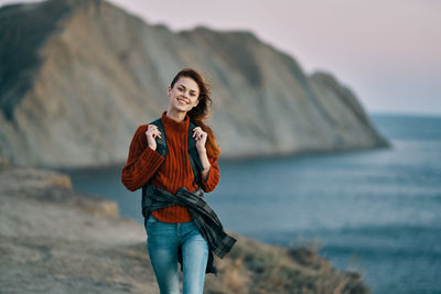 Portrait of smiling young woman standing on beach