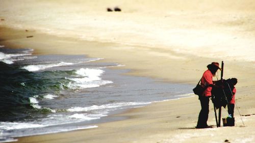 Rear view of friends enjoying at beach