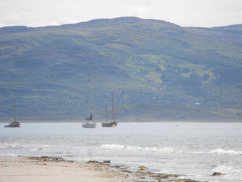 Sailboat on sea against mountains