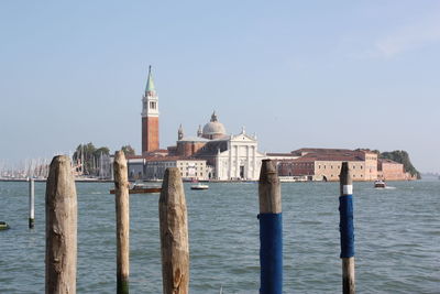 Wooden posts in sea against sky