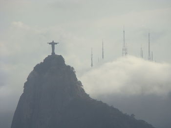 Low angle view of cross on mountain against sky