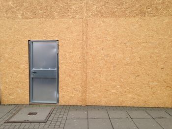 Closed metallic door of wooden wall by sidewalk