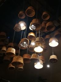 Low angle view of illuminated light bulbs hanging at night