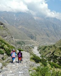 Rear view of people walking on mountain against sky