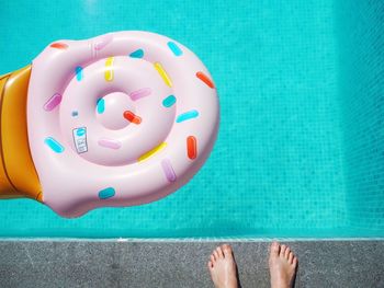 Low section of woman by inflatable in swimming pool