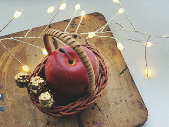 High angle view of apples in basket and christmas lights on table