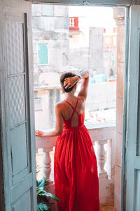 Rear view of woman photographing through window