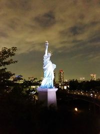 Statue of illuminated city against cloudy sky