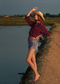 Rear view of woman with arms raised standing at beach