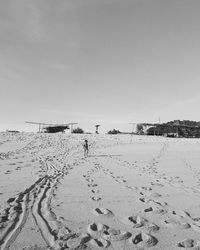 Footprints on sand at beach against clear sky