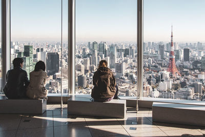 Rear view of woman looking at cityscape against sky