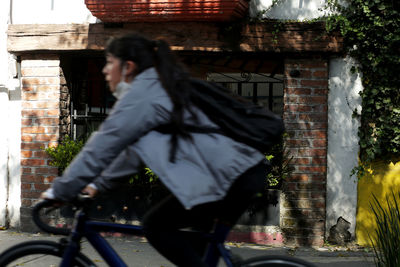 Side view of woman riding bicycle against building