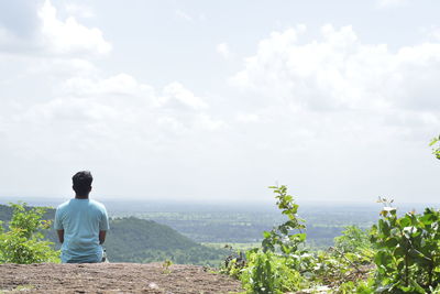 Rear view of man looking at sea against sky