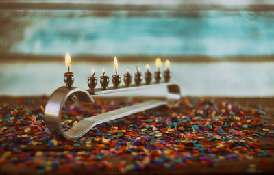 Close-up of burning oil lamp on table against wall