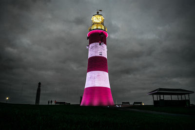 Low angle view of lighthouse against buildings and sky