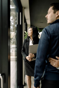 Real estate agent looking through window while standing with couple at new home