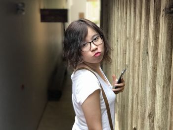 Side view portrait of young woman using phone amidst walls