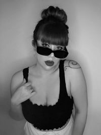 Portrait of man wearing sunglasses standing against wall