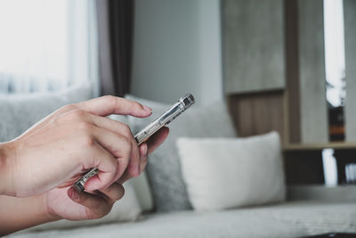 Midsection of woman holding camera at home