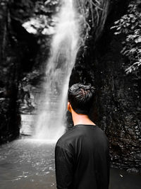 Rear view of man against waterfall in forest