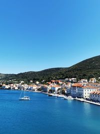 Boats in sea against clear blue sky