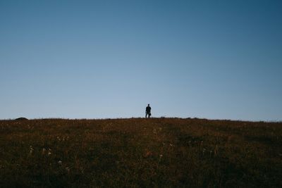 Silhouette of woman standing on field against clear sky