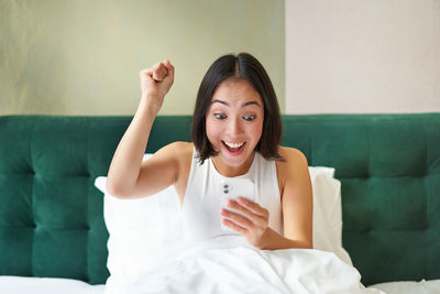 Portrait of young woman sitting on bed at home