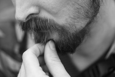 Close-up of mid adult man touching beard