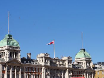 Low angle view of flag against built structure against clear sky