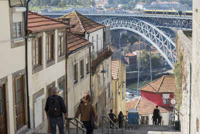 Rear view of people on steps against dom luis i bridge in city