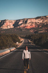 Rear view of man standing on road against mountain