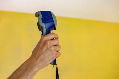 Close-up of man holding camera against wall