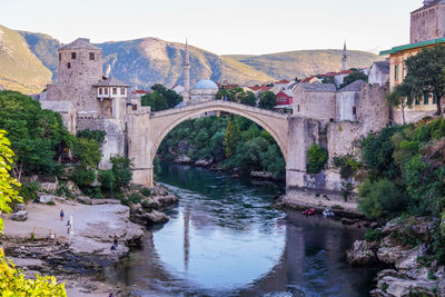 Arch bridge over river against buildings