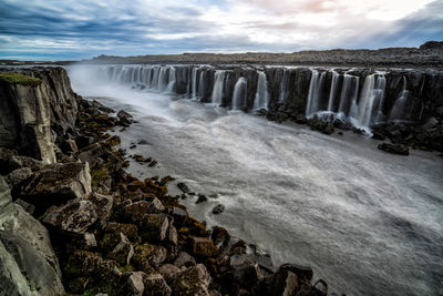 Scenic view of waterfall against sky