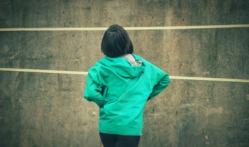 Rear view of a boy standing against wall