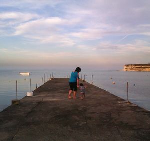 Rear view of man standing at beach against sky