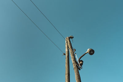 Low angle view of electricity pylon against clear blue sky