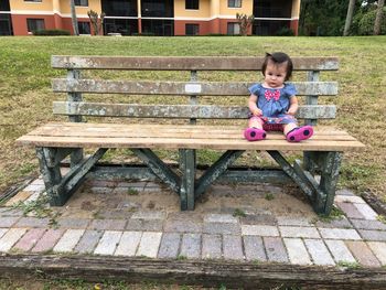 Portrait of girl sitting on bench in park