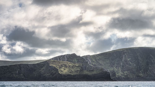 Scenic view of sea by mountains against sky