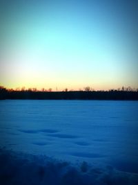 Scenic view of frozen lake against clear sky during sunset