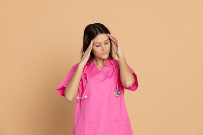 Young woman standing against pink background