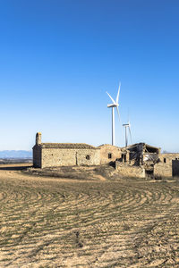 Wind turbines in between agricultural fields and an abandoned old town in catalonia spain