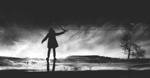 Boy standing on beach against sky