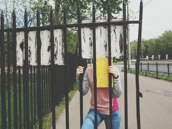 Man standing by railing against plants