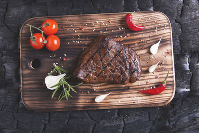 Directly above shot of grilled meat with tomatoes and spices on table