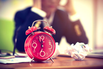 Midsection of stressed businessman with red alarm clock on desk