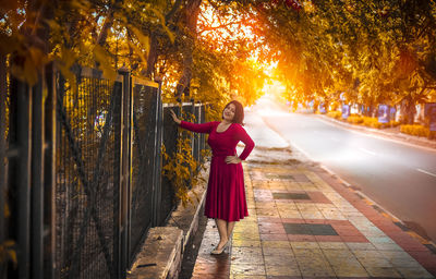 Portrait of woman standing in footpath during sunset