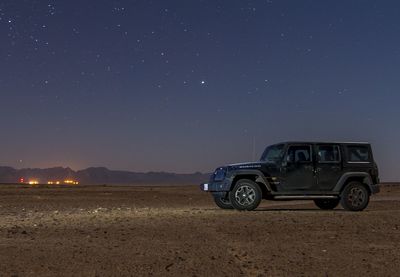 Off-road vehicle parked at desert against sky